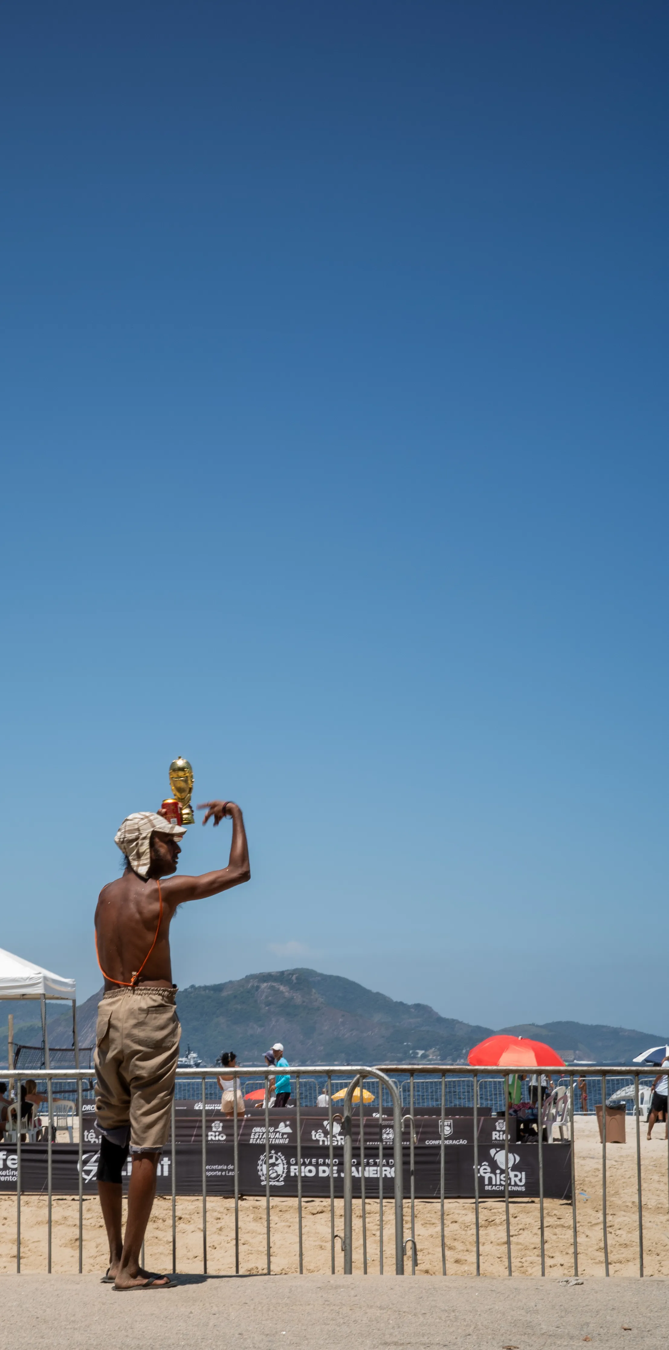 Vendedor ambulante equilibrando um troféu da Copa do Mundo na cabeça na praia do Rio de Janeiro